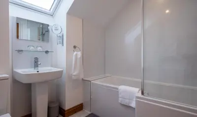 a white bathroom with a sink and a shower at Sherriff in Penrith