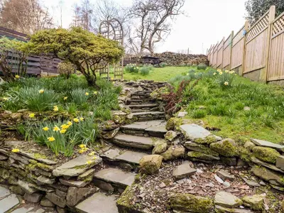 a garden with a stone path and flowers at Gunpowder Cottage in Elterwater
