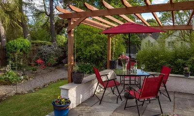a patio with a table and chairs and an umbrella at Artists Hideaway in Portinscale
