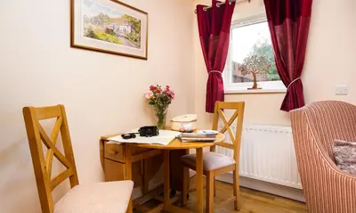 a small table and chairs in a room with a window at Artists Hideaway in Portinscale