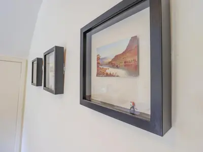 a row of framed art on a wall at Croft in Grasmere