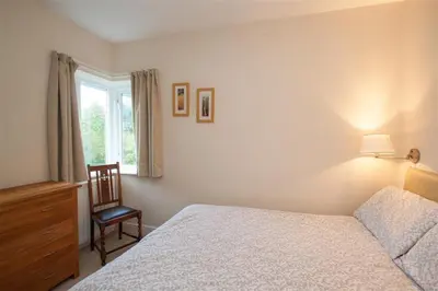 a bedroom with a bed and a chair and a window at The Haven in Keswick