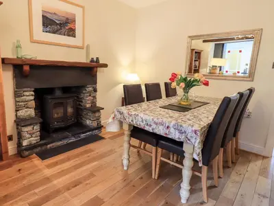 a dining room with a table and a fireplace at Holmdale in Ambleside