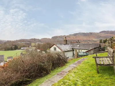 a bench sitting in the grass next to a house at Underfell in Ambleside
