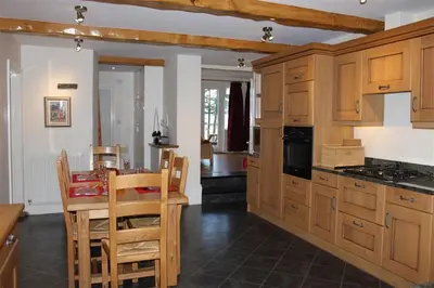 a kitchen with wooden cabinets and a table with chairs at Pen Cottage in Keswick