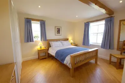 a bedroom with a bed and two windows with blue curtains at Pen Cottage in Keswick