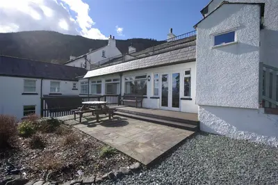 a patio with a picnic table next to a building at Pen Cottage in Keswick