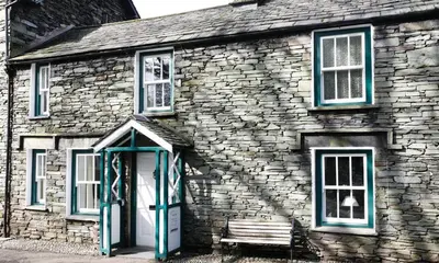 a stone building with a bench in front of it at Dove Holme Cottage in Grasmere