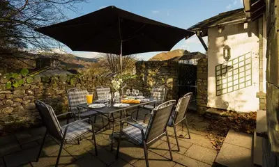a table with chairs and an umbrella on a patio at Lanterns At Grasmere in Grasmere