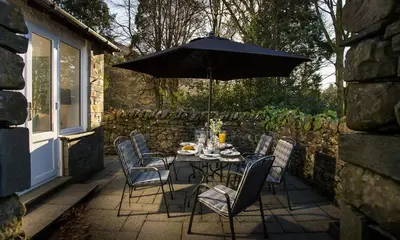 a table and chairs with an umbrella on a patio at Lanterns At Grasmere in Grasmere
