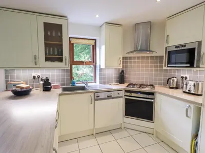 a kitchen with white cabinets and a sink at Drystones in Grasmere