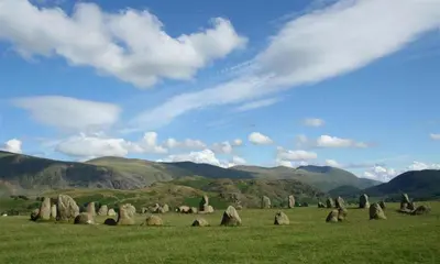 a field with rocks in a field with mountains at The Cats Bield in Keswick