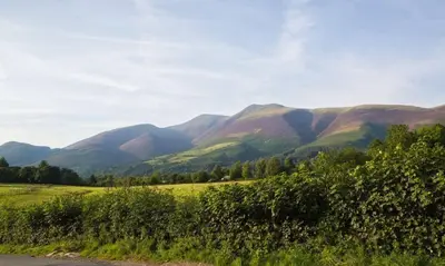 a view of a mountain range with a road at Scots Pine in Keswick