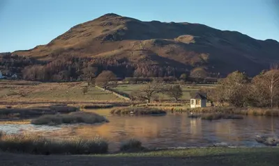 a mountain with a house in the middle of a lake at Cedar Nook in Loweswater