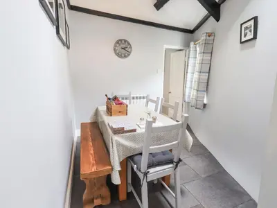 a dining room with a table and chairs and a clock at The Smithy in Borrowdale Valley