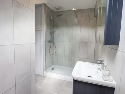 a bathroom with a shower and a sink and a tub at The Smithy in Borrowdale Valley