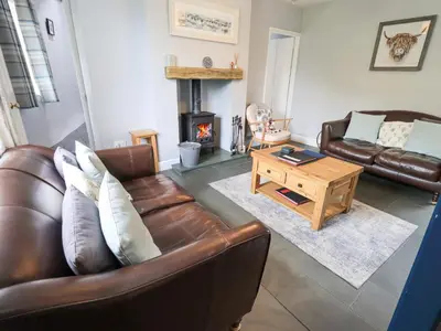 a living room with a leather couch and a coffee table at The Smithy in Borrowdale Valley