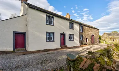 a white house with red doors on a street at Low Longthwaite Farm in Watermillock