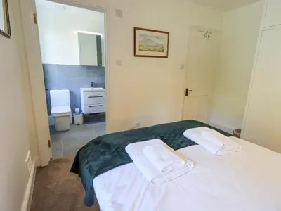 a bedroom with a white bed with two towels on it at Rowan Cottage in Grasmere