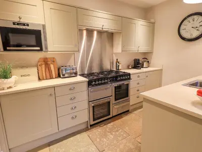 a kitchen with white cabinets and a stove top oven at Honeywood House in Grasmere