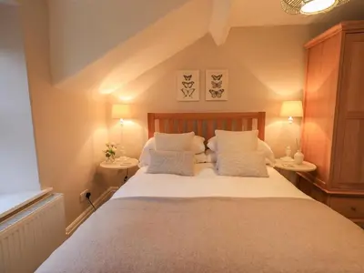 a bedroom with a large bed with white sheets and pillows at Honeywood House in Grasmere
