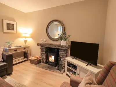 a living room with a fireplace and a flat screen tv at Honeywood House in Grasmere