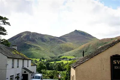 a view of a mountain range with a car driving down a street at Swinside Cottage in Keswick