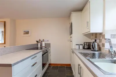a kitchen with white cabinets and a sink at Swinside Cottage in Keswick