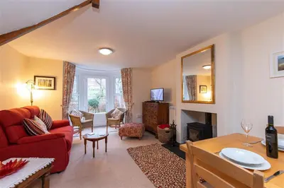 a living room with a red couch and a table at Swinside Cottage in Keswick