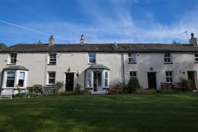 a large white house with a lawn in front of it at Swinside Cottage in Keswick