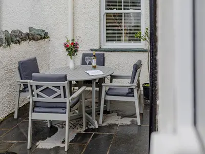 a table and chairs on a patio with a bottle of wine at Oak House in Keswick