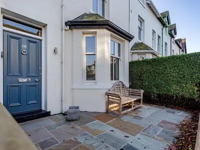 a bench sitting outside of a house with a blue door at Oak House in Keswick