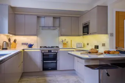 a kitchen with white cabinets and appliances and a plate of food at The Old Police House in Grasmere