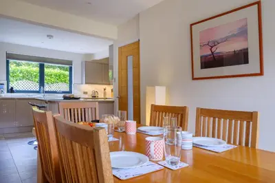 a dining room table with chairs and a wooden table with plates at The Old Police House in Grasmere