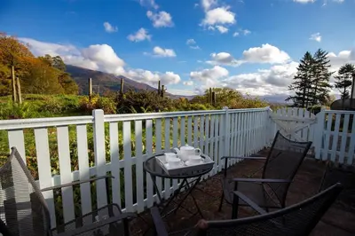 a patio with two chairs and a table on a white fence at Cygnet Cottage in Keswick