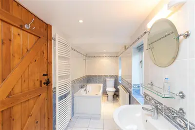 a bathroom with a sink and a toilet and a mirror at Cygnet Cottage in Keswick