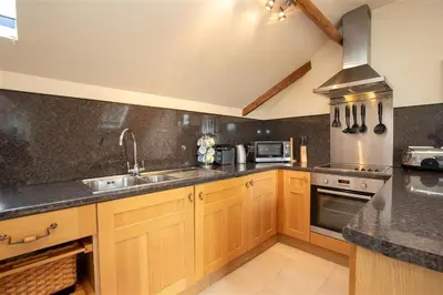 a kitchen with wooden cabinets and a sink and a stove at Cygnet Cottage in Keswick