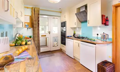 a kitchen with white cabinets and a wooden table at Lingmoor View in Ambleside