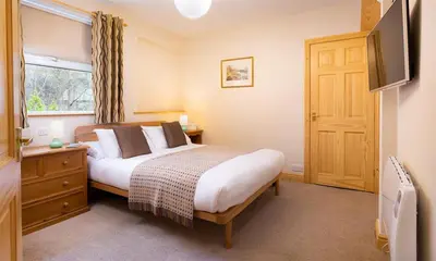 a bedroom with a bed and a window and a television at Lingmoor View in Ambleside