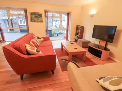 a living room with a red couch and a flat screen tv at Molly's Cottage in Grasmere