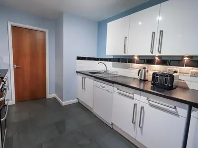 a kitchen with white cabinets and a black counter top at Molly's Cottage in Grasmere