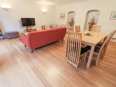 a living room with a red couch and a wooden table at Molly's Cottage in Grasmere