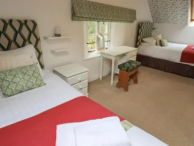 a bedroom with two beds and a desk and a window at North Lodge in Grasmere