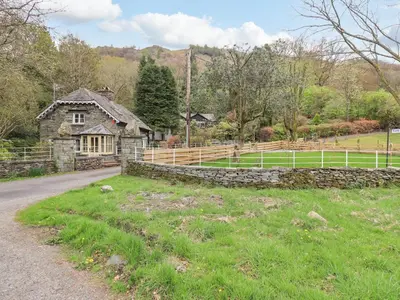 an old house with a stone wall and a road at North Lodge in Grasmere