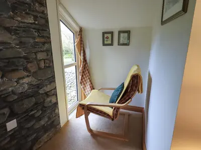a wooden chair in a room with a window at Beckside Studio in Patterdale
