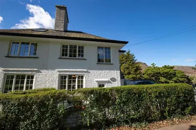 a white house with a hedge in front of it at Crozier Cottage in Ambleside