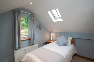 a bedroom with a bed and a window at Dancing Beck Cottage in Keswick