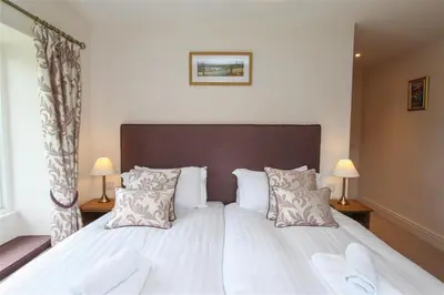 a bedroom with a large bed with white sheets and pillows at Elterwater Lodge in Little Langdale