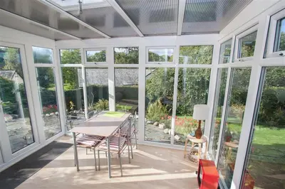 a conservatory with a table and chairs and windows at Brimbles in Keswick