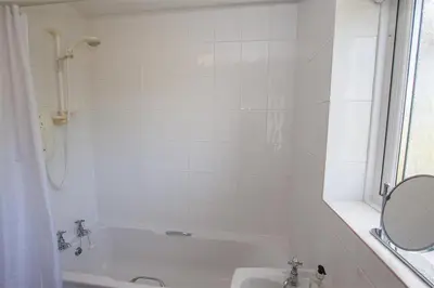 a white bathroom with a tub and a sink at Brimbles in Keswick